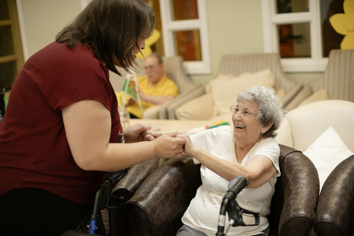 A caregiver walking with an older woman using a walker